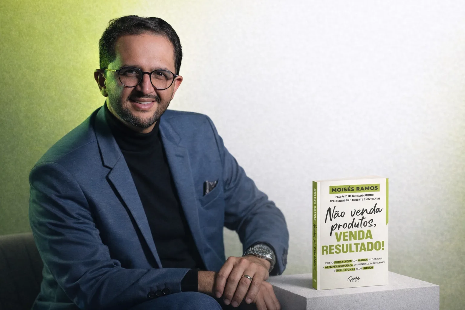 Moisés Ramos sentado ao lado de um exemplar do livro Não venda produtos, venda resultado!